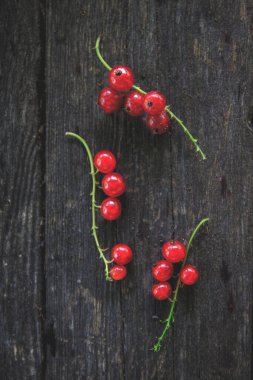 Eski, koyu bir ahşap zemin üzerinde sulu taze kırmızı üzümler, üst manzara.