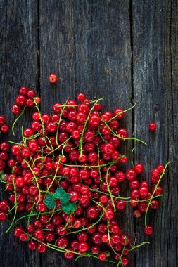 Eski, koyu bir ahşap zemin üzerinde sulu taze kırmızı üzümler, üst manzara.