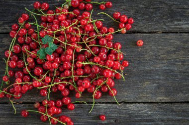 Eski, koyu bir ahşap zemin üzerinde sulu taze kırmızı üzümler, üst manzara..