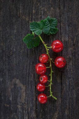Eski, koyu bir ahşap zemin üzerinde sulu taze kırmızı üzümler, üst manzara..