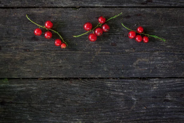 Eski, koyu bir ahşap zemin üzerinde sulu taze kırmızı üzümler, üst manzara..