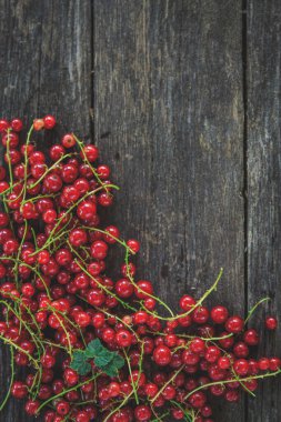Eski, koyu bir ahşap zemin üzerinde sulu taze kırmızı üzümler, üst manzara..