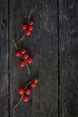 Eski, koyu bir ahşap zemin üzerinde sulu taze kırmızı üzümler, üst manzara..