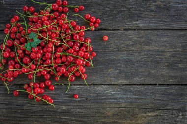 Eski, koyu bir ahşap zemin üzerinde sulu taze kırmızı üzümler, üst manzara..