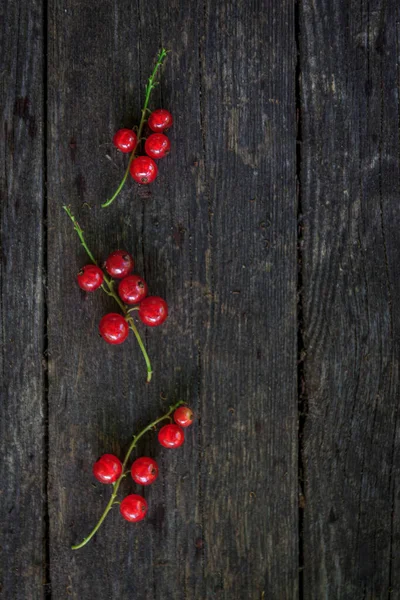 Eski, koyu bir ahşap zemin üzerinde sulu taze kırmızı üzümler, üst manzara..