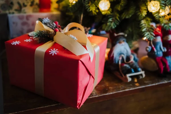 Beautifully wrapped red gift box under the christmas tree, top view — Stock Photo, Image