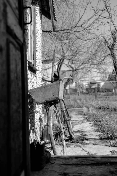 Bicicleta velha fica perto da parede, vista para trás. Foto monocromática, preto e branco — Fotografia de Stock