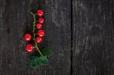 Eski, koyu bir ahşap zemin üzerinde sulu taze kırmızı üzümler, üst manzara.