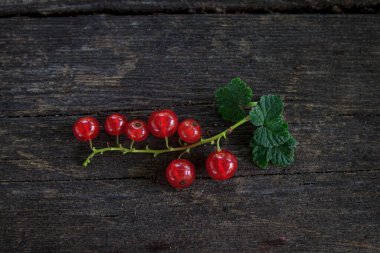 Eski, koyu bir ahşap zemin üzerinde sulu taze kırmızı üzümler, üst manzara.