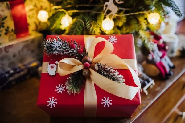 Beautifully wrapped red gift box under the christmas tree, top view — Stock Photo, Image