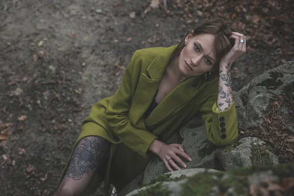 Modna Młoda Kobieta Zielonym Płaszczu Pozująca Lesie Niedaleko Kamienia Portret — Zdjęcie stockowe