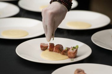 Beyaz eldivenli şefin domuz pastırmasına sarılmış lezzetli kızarmış domuz eti servis edişinin yakın çekimi. Geleneksel İrlanda yemeği sarımsaklı domuz filetosu..