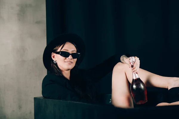 Дівчина Чорній Куртці Капелюсі Позує Чорній Ванні Пляшка Рожевого Шампанського — стокове фото