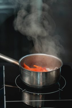 Modern mutfakta tencere ve sebzeler ve indüksiyon sobası.