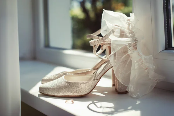 White wedding high heel shoes on the white windowsill in sunlight