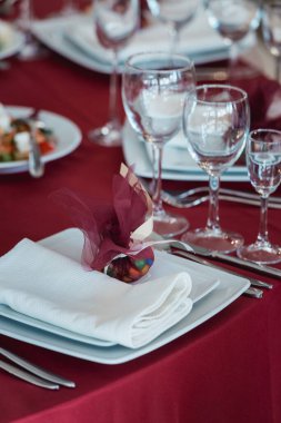Kırmızı masa örtüsü ile servis edilen kaliteli bir restoran masası. Tabakta hediye
