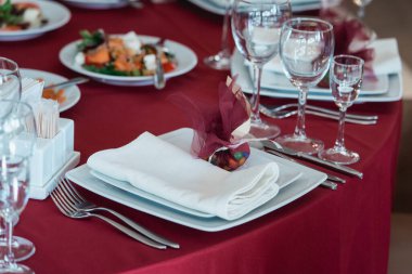 Kırmızı masa örtüsü ile servis edilen kaliteli bir restoran masası. Tabakta hediye