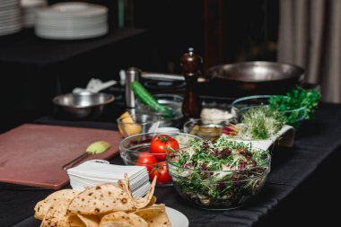 Taco için ürünlerle dolu bir masa. Restorandaki şef müşterilerin önünde lahana salatası ve salsa soslu baharatlı karidesli taco yapacak..