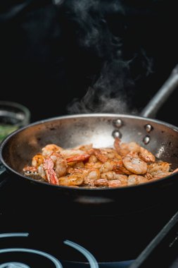 Tavada karides var. Gıdanın termal işlemesi. Restoranda elektrikli tencere. Şef baharatlı karidesli taco yapacak.