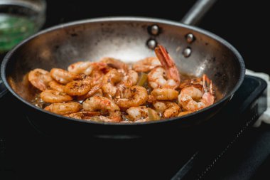Tavada karides var. Gıdanın termal işlemesi. Restoranda elektrikli tencere. Şef baharatlı karidesli taco yapacak.