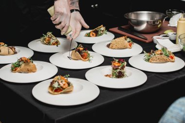 Restorandaki şef lahana salatası ve salsa soslu baharatlı karidesli taco yapıyor. Şef taconun üzerine sos döker.