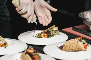 Restorandaki şef lahana salatası ve salsa soslu baharatlı karidesli taco yapıyor. Şef taconun üzerine sos döker.