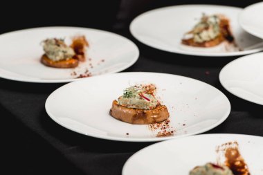 Siyah bir masada, üzerinde fırında bal kabağı ve avokado sosu olan birkaç beyaz tabak. Restoranda Meksika mutfağı günü.