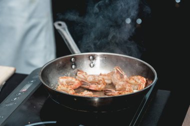 Tavada karides var. Gıdanın termal işlemesi. Restoranda elektrikli tencere. Şef baharatlı karidesli taco yapacak.
