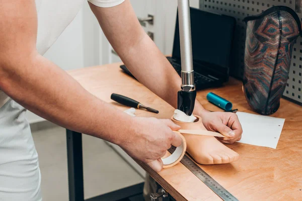 Protez teknisyeni atölyedeki ahşap bir masada protez kalıplarını kontrol ediyor.