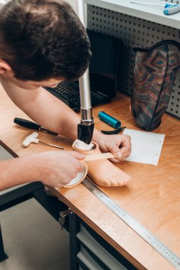 Protez teknisyeni atölyedeki ahşap bir masada protez kalıplarını kontrol ediyor.