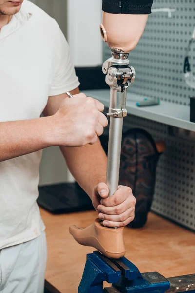 Technician checking artificial limb while at desk in workshop, adjusting it and checking for quality. the latest prosthetic technologies