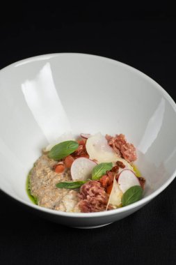 Lezzetli yulaf ezmesi, domuz pastırması ve sebzeli kase siyah masa örtüsü.