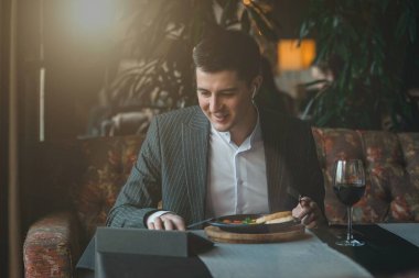 Adam tabletini sağlıklı kahvaltı yaparken kullanıyor Shakshuka - yumurta, domates ve baharatlar kapalı bir restoranda eski ahşap bir kalas üzerinde dökme demir güveç.