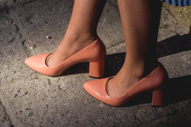 Sokakta kaldırımda duran bej renkli deri topuklu genç bayan. Sıradan sokak modası..