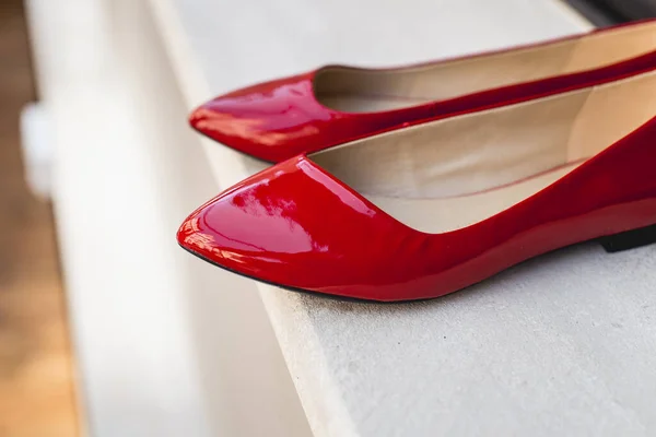 Leather red womens shoes on a white wooden shelf. Fashion, minimal fashion concept, womens shoes, accessories. red womens lacquered leather shoes