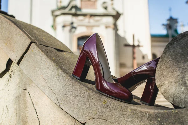 Leather cherry womens shoes on a stone wall. fashion concept, womens shoes, accessories. burgundy womens lacquered leather shoes