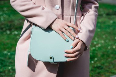 Küçük mavi çantalı, bej ceketli şık bir kadın..