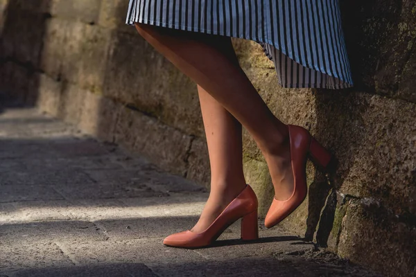 Eine junge Frau in beigen Lederabsätzen steht auf dem Bürgersteig der Stadtstraße. Lässiger Streetfashion-Look. — Stockfoto