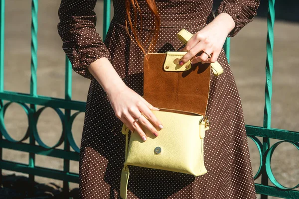 Fashionable young woman in brown dress with yellow handbag in hand on the city streets. Fashion. — Stock Photo, Image