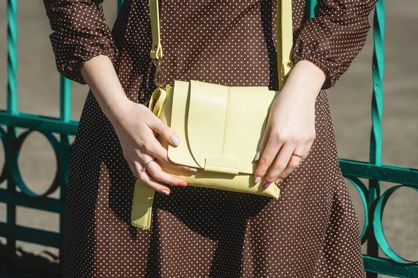 Fashionable young woman in brown dress with yellow handbag in hand on the city streets. Fashion. — Stock Photo, Image