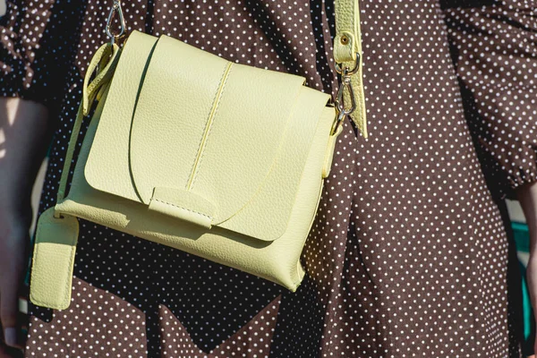 Fashionable young woman in brown dress with yellow handbag in hand on the city streets. Fashion. — Stock Photo, Image