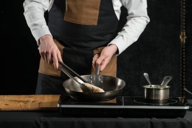 Adam indüksiyon ocağında et ve sos pişiriyor.