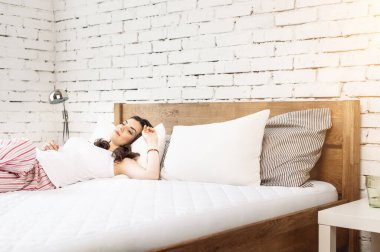 Beyaz bir yastığa uzanmış bir kız ve tahta bir yatakta bir yatak. Rahat uyku kavramı. ortopedik yatak ve yastık