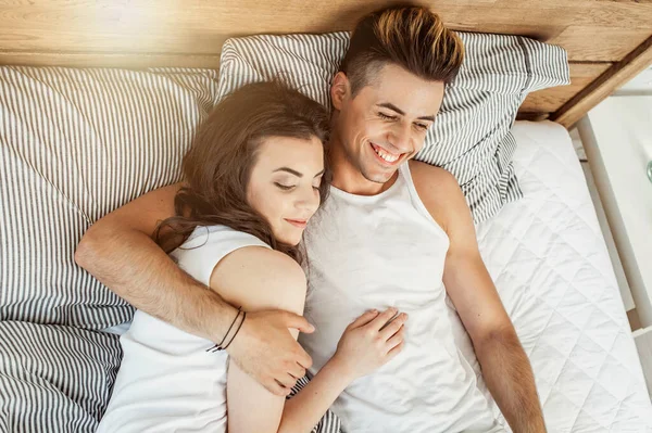Νεαρό ερωτευμένο ζευγάρι με πιτζάμες στο κρεβάτι — Φωτογραφία Αρχείου