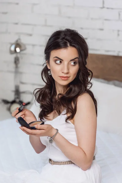 Žena aplikující make-up při sezení na posteli v hotelovém pokoji — Stock fotografie