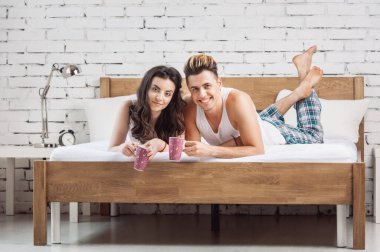 Neşeli çift evlerinde yatağında bir fincan çay içiyor.