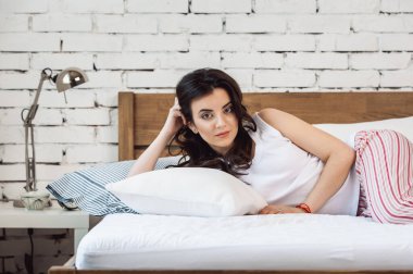 Beyaz bir yastığa uzanmış bir kız ve tahta bir yatakta bir yatak. Rahat uyku kavramı. ortopedik yatak ve yastık