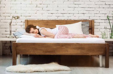 Beyaz yastıkta uyuyan bir kadın ve tahta yatakta yatan bir yatak. Rahat uyku kavramı. ortopedik yatak ve yastık