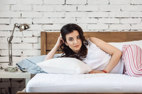 Beyaz bir yastığa uzanmış bir kız ve tahta bir yatakta bir yatak. Rahat uyku kavramı. ortopedik yatak ve yastık