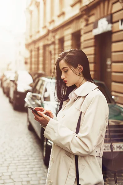 Uma mulher na rua usa um telemóvel. compras online. Utilização de aplicações móveis. — Fotografia de Stock